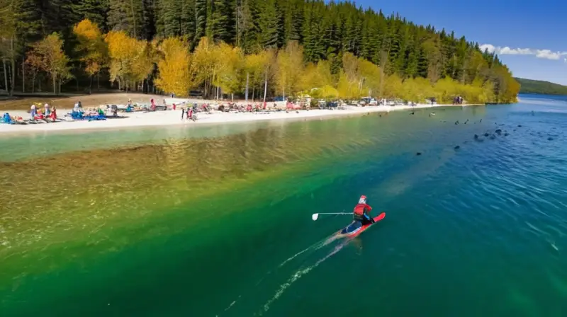 Un lago soleado con un esquiador en traje rojo surcando el agua, rodeado de árboles verdes y una playa animada